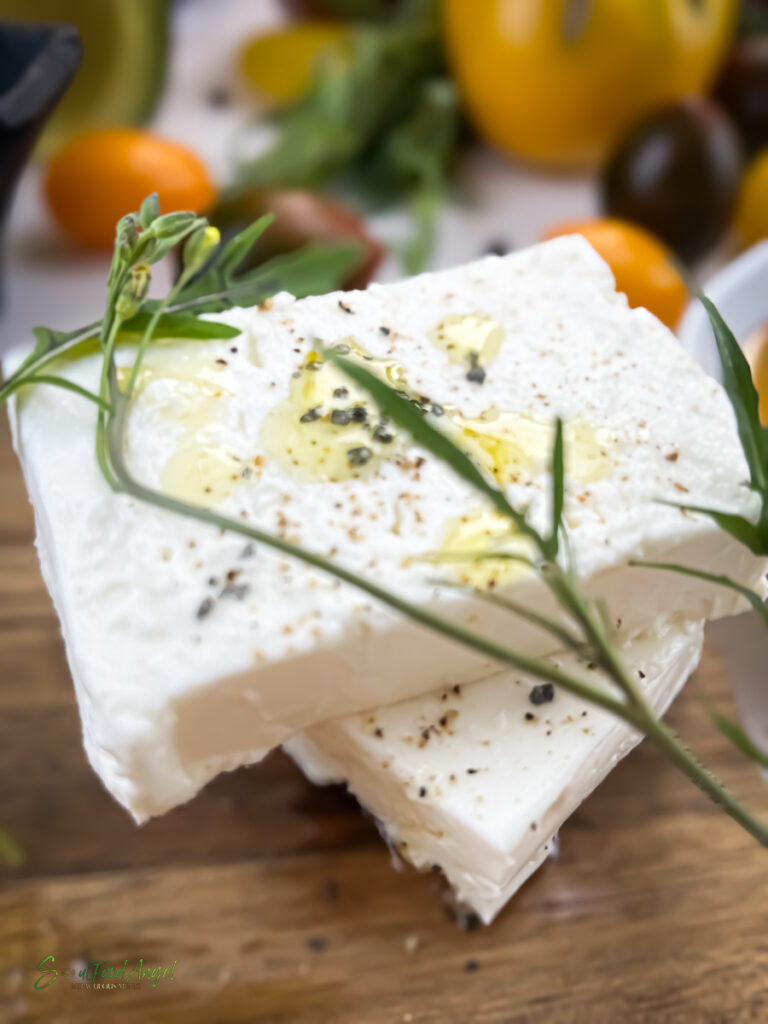 Feta cheese garnished with herbs, cracked pepper and olive oil